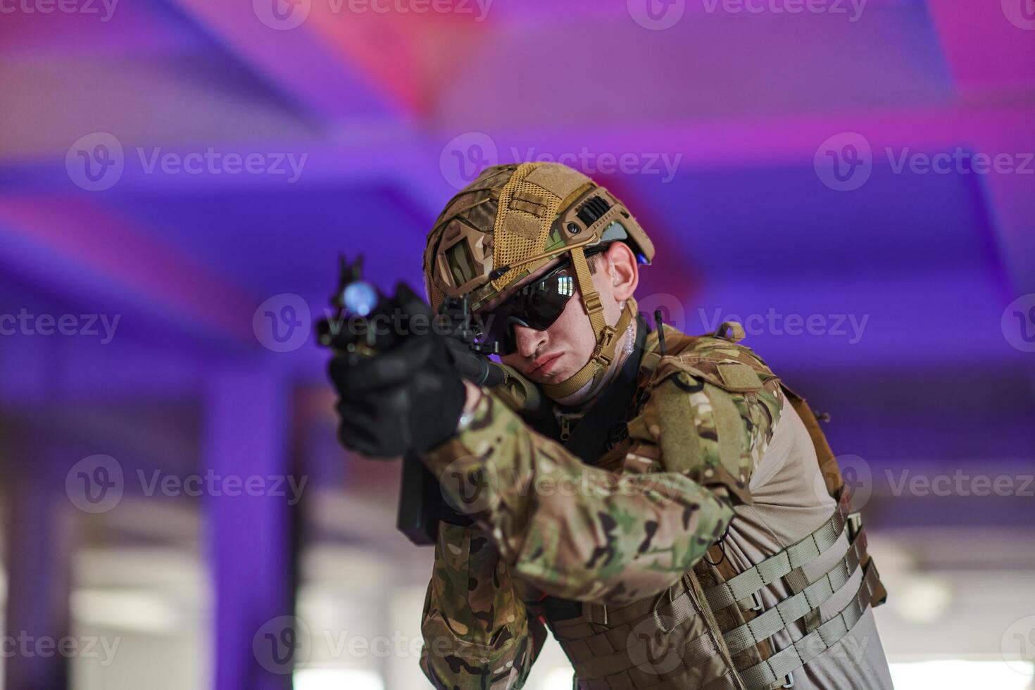 A professional soldier undertakes a perilous mission in an abandoned building illuminated by neon blue and purple lights photo