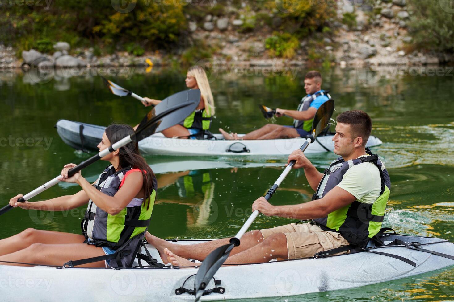 A group of friends enjoying having fun and kayaking while exploring the calm river, surrounding forest and large natural river canyons photo
