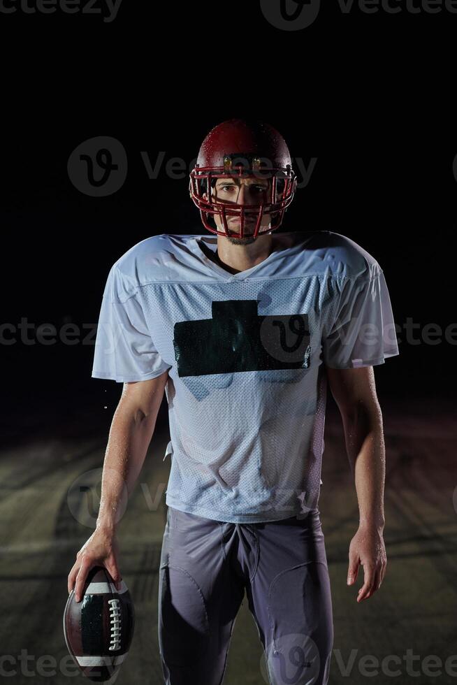 American Football Field. Lonely Athlete Warrior Standing on a Field Holds his Helmet and Ready to Play. Player Preparing to Run, Attack and Score Touchdown. photo