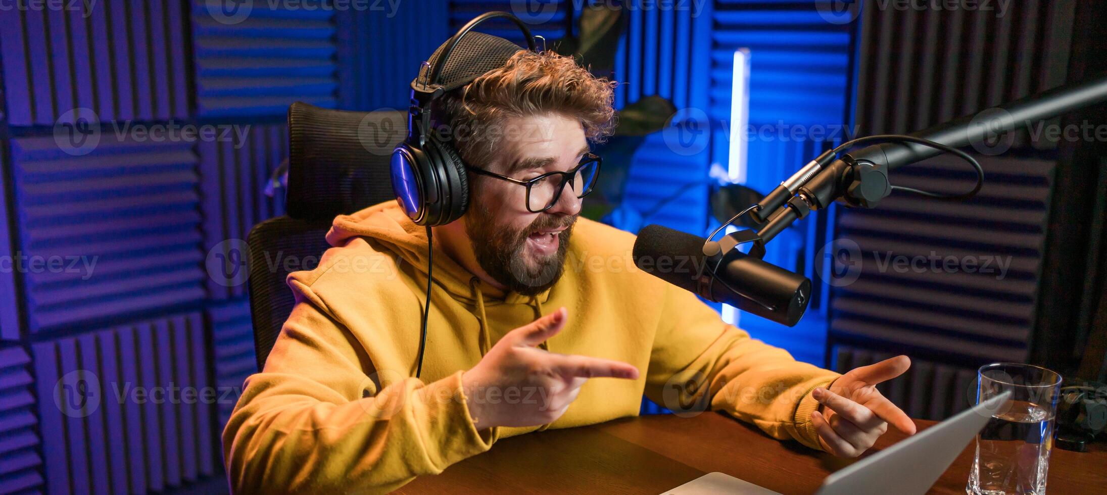 Banner man recording podcast in studio copy space. Confident man with headphones and microphone recording a podcast. Happy guy talking on web radio. photo