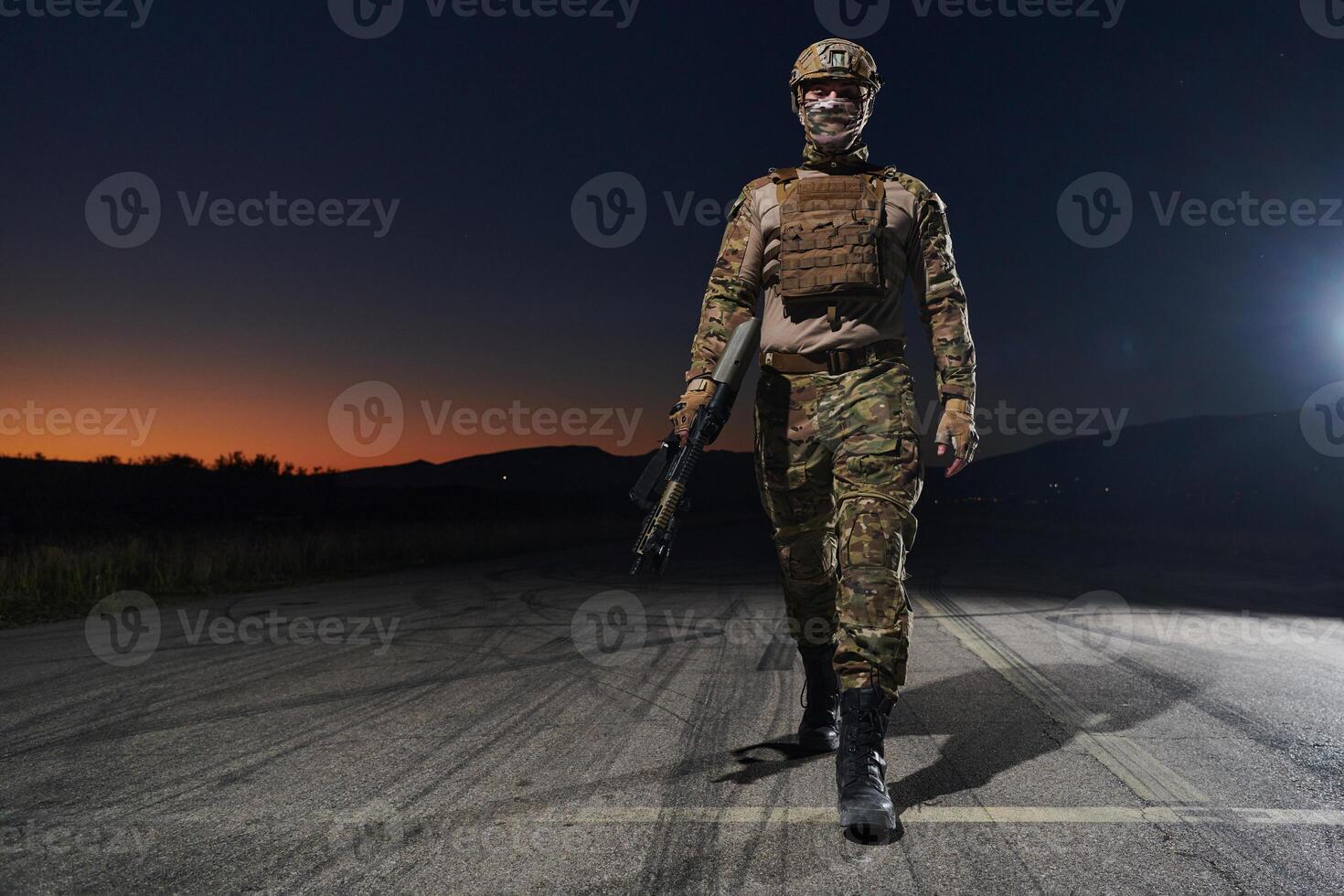 A professional soldier in full military gear striding through the dark night as he embarks on a perilous military mission photo