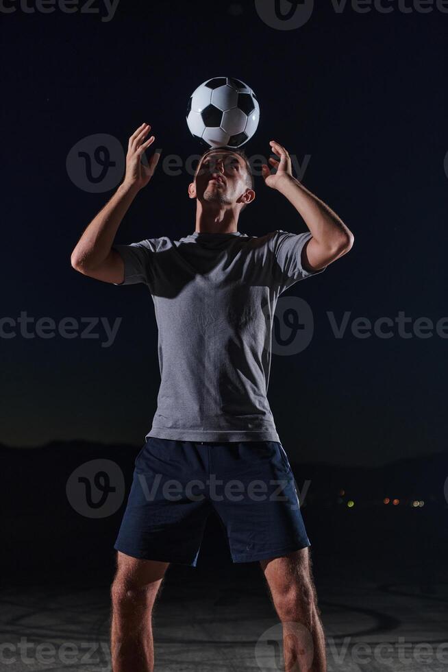 Portrait of a young handsome soccer player man on a street playing with a football ball photo