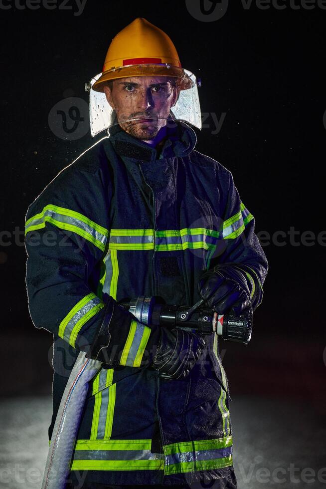 Firefighter using a water hose to eliminate a fire hazard. Team of female and male firemen in dangerous rescue mission. photo