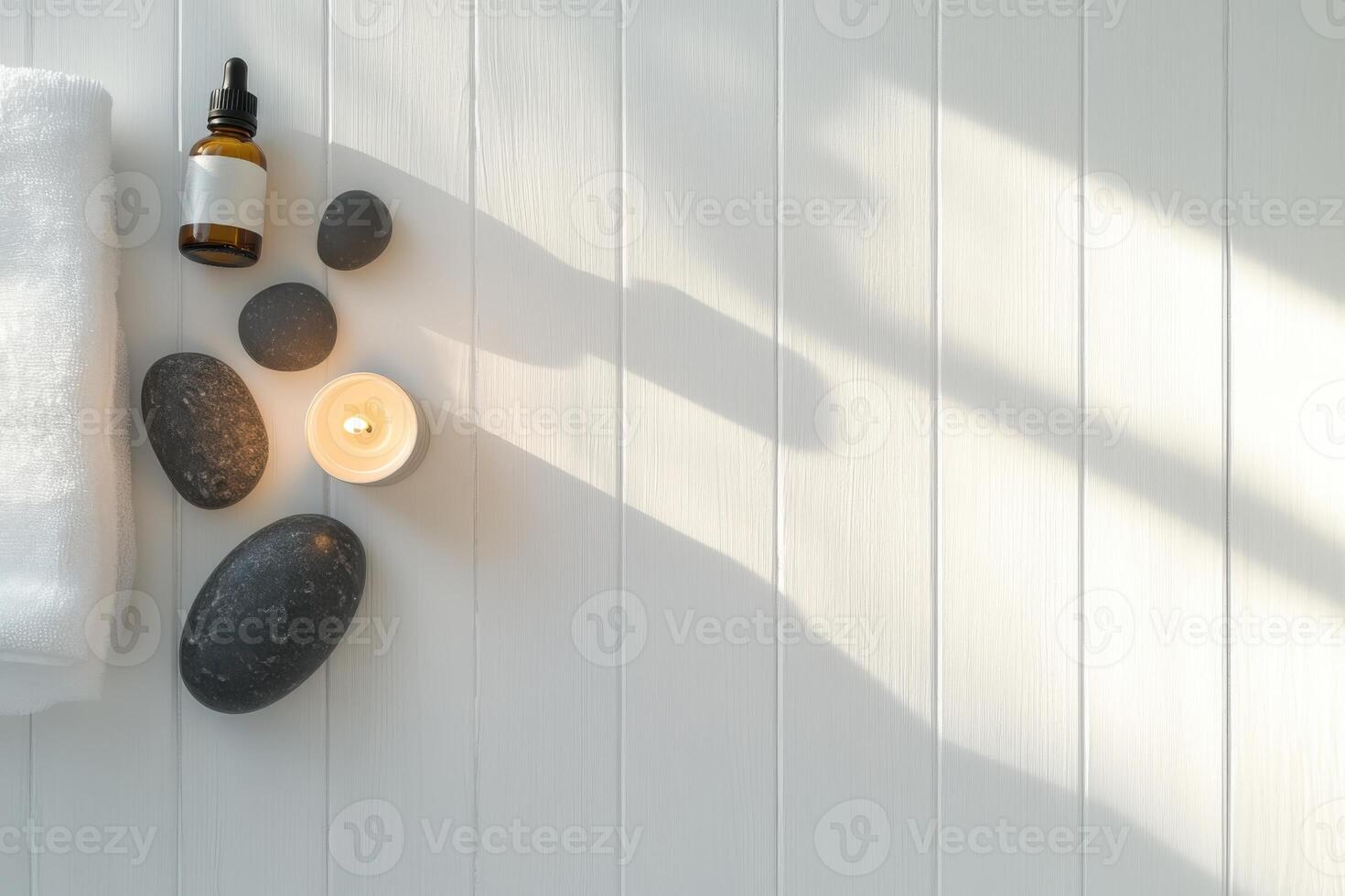 A minimalist composition featuring massage stones, essential oil bottles, and a lit candle arranged on a white wooden table. photo