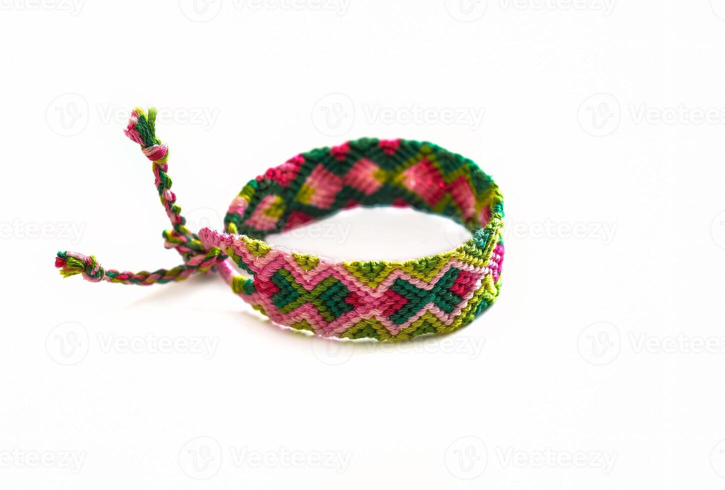 pink green woven DIY friendship bracelet handmade of embroidery bright thread with knots isolated on white background photo