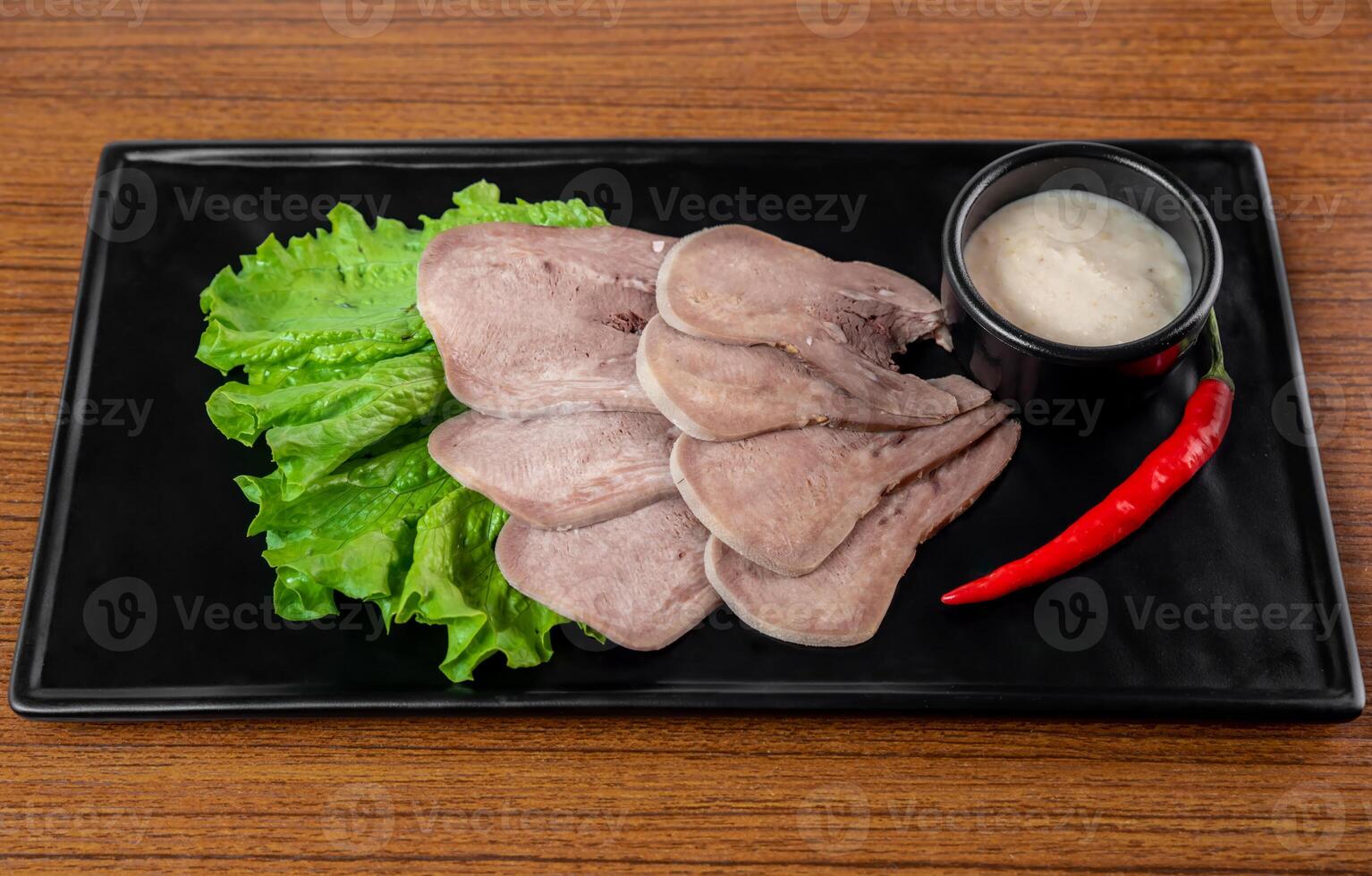 Appetizer with slices of beef on a black plate on a white background photo