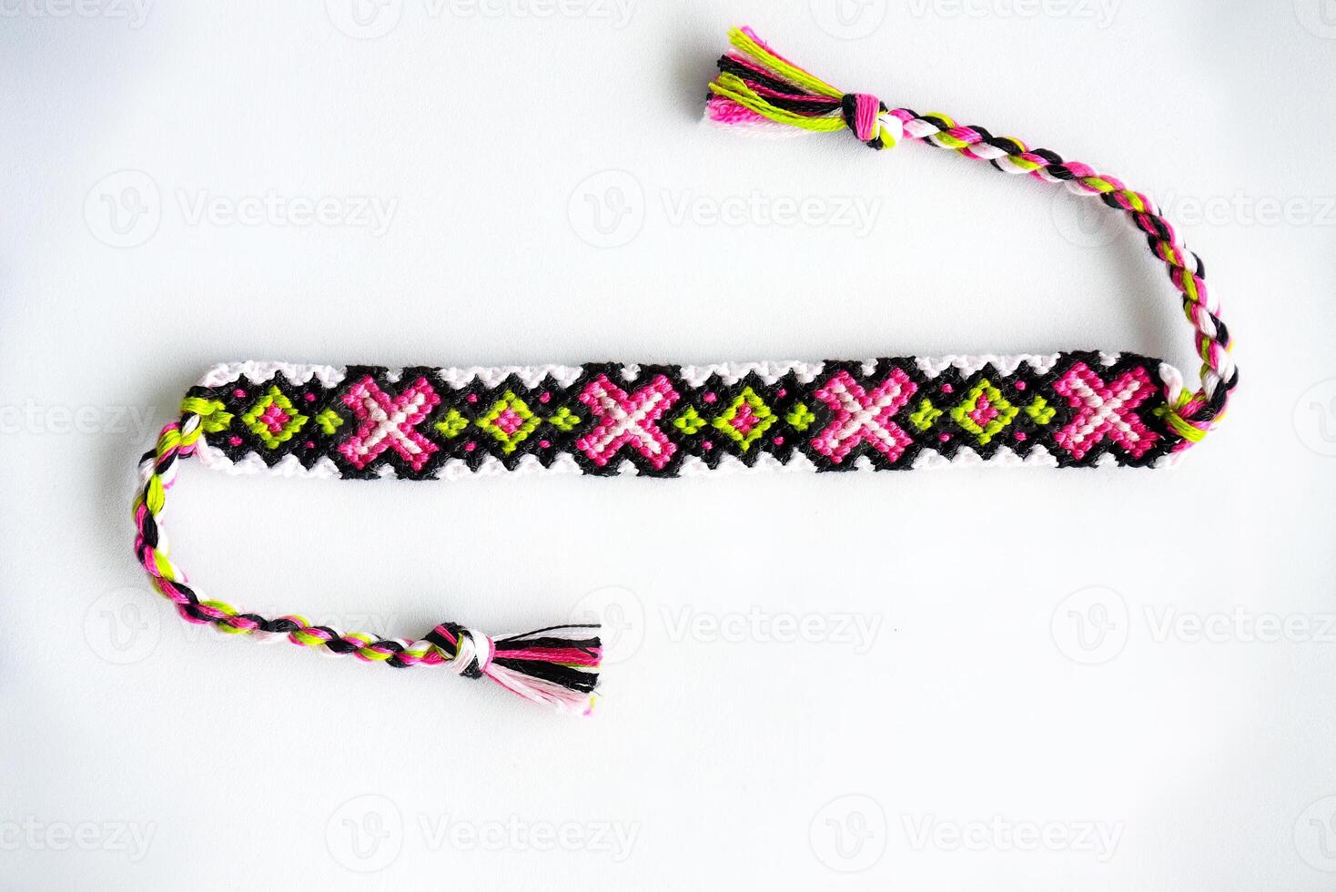 one pink DIY friendship bracelet handmade of embroidery bright thread with knots isolated on white background photo