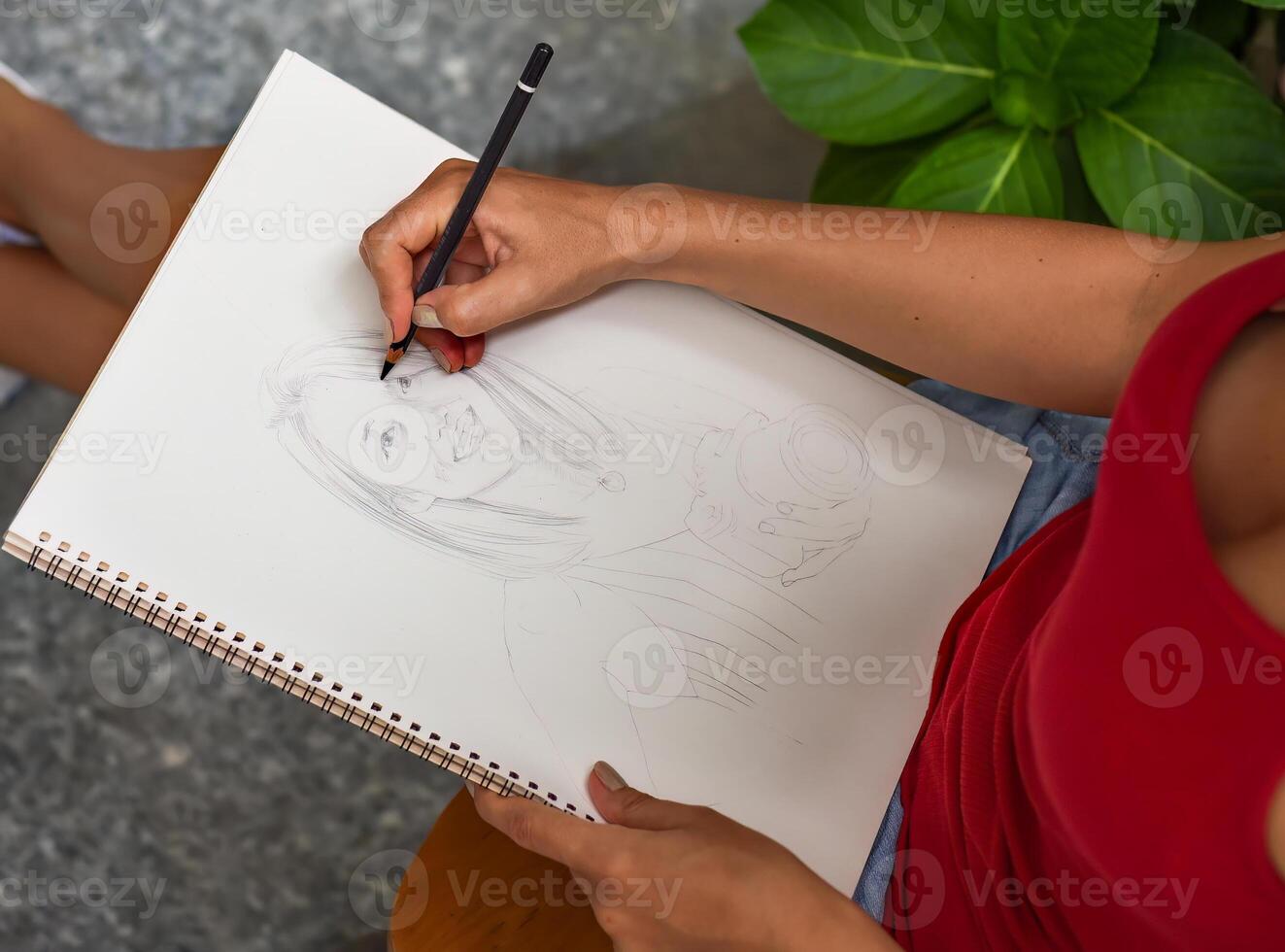Ukrainian woman artist and illustrator thinking about idea of a drawing, sitting on a chair with a pencil photo