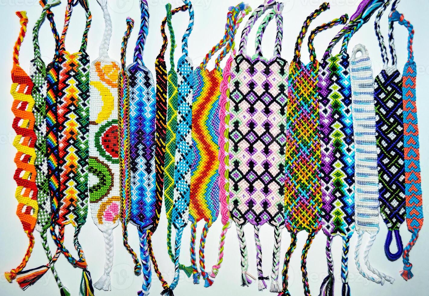 woven DIY friendship bracelets handmade of embroidery bright thread with knots isolated on white background top view photo