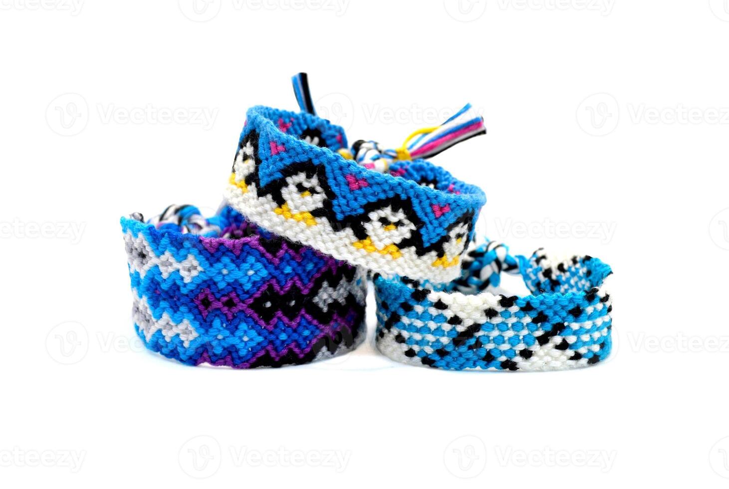 Selective focus of tied woven friendship bracelet with cute pattern Penguins hold their paws. Handmade of floss thread, isolated on white background. bracelet for women and children. photo