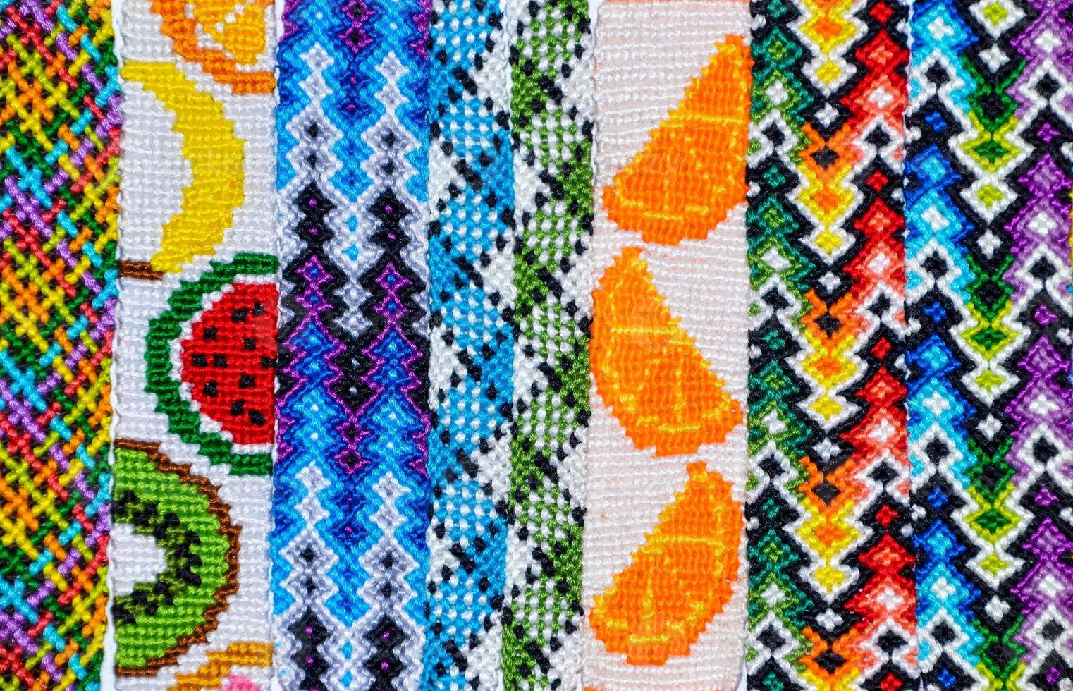Multicolored woven DIY friendship bracelets handmade of embroidery bright thread with knots isolated on white background top view photo