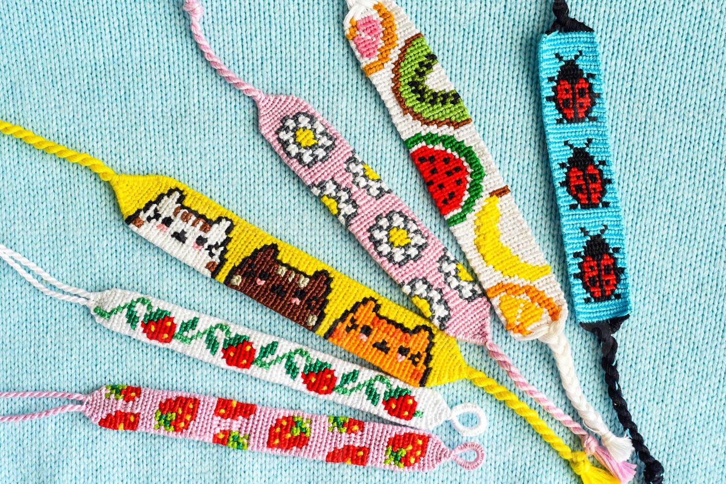 DIY friendship bracelets with alpha pattern Strawberry on woven background photo