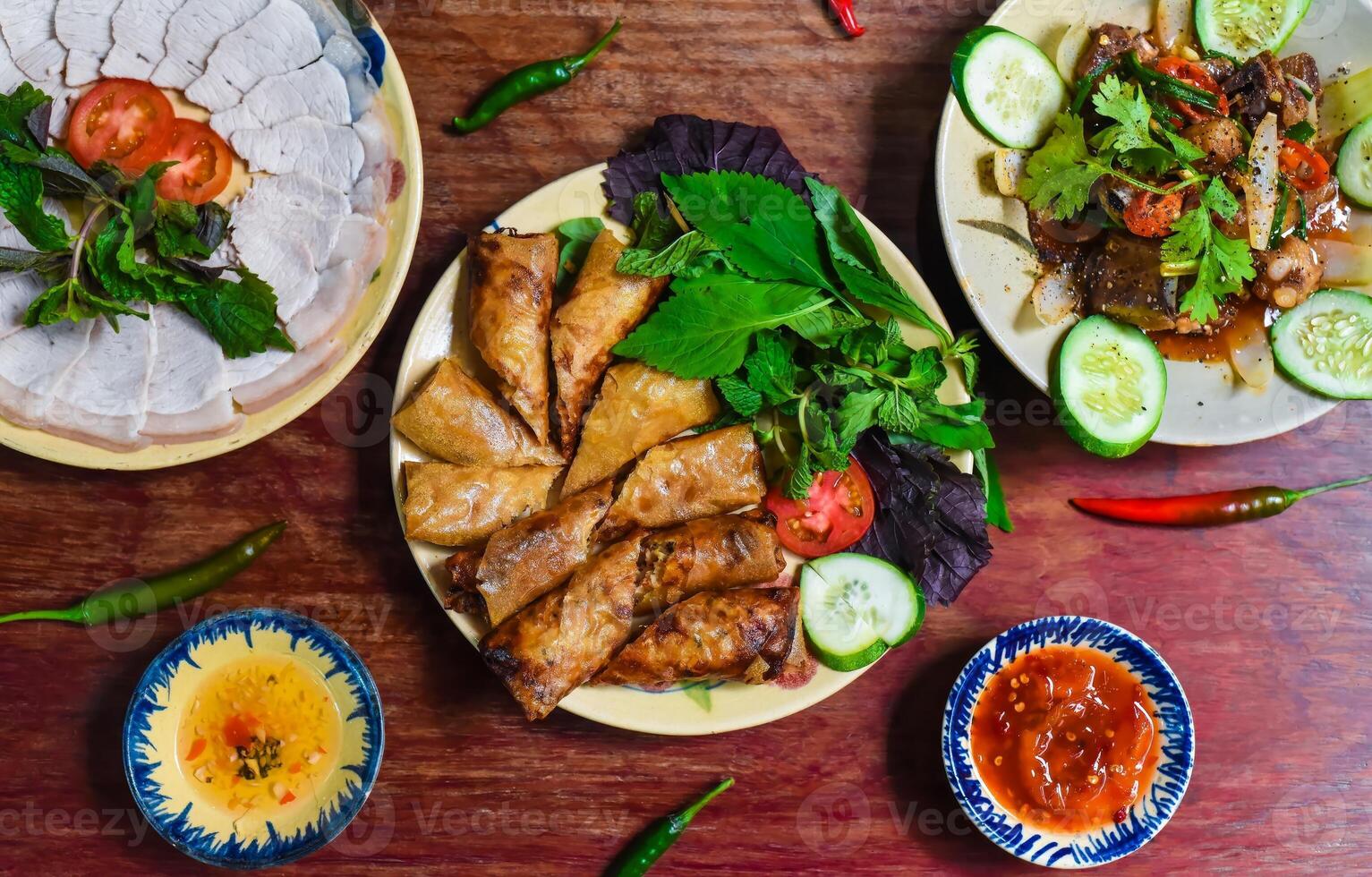 Traditional fried vietnamese spring rolls with pork, rice paper with sauces, meat slices and beef stew photo