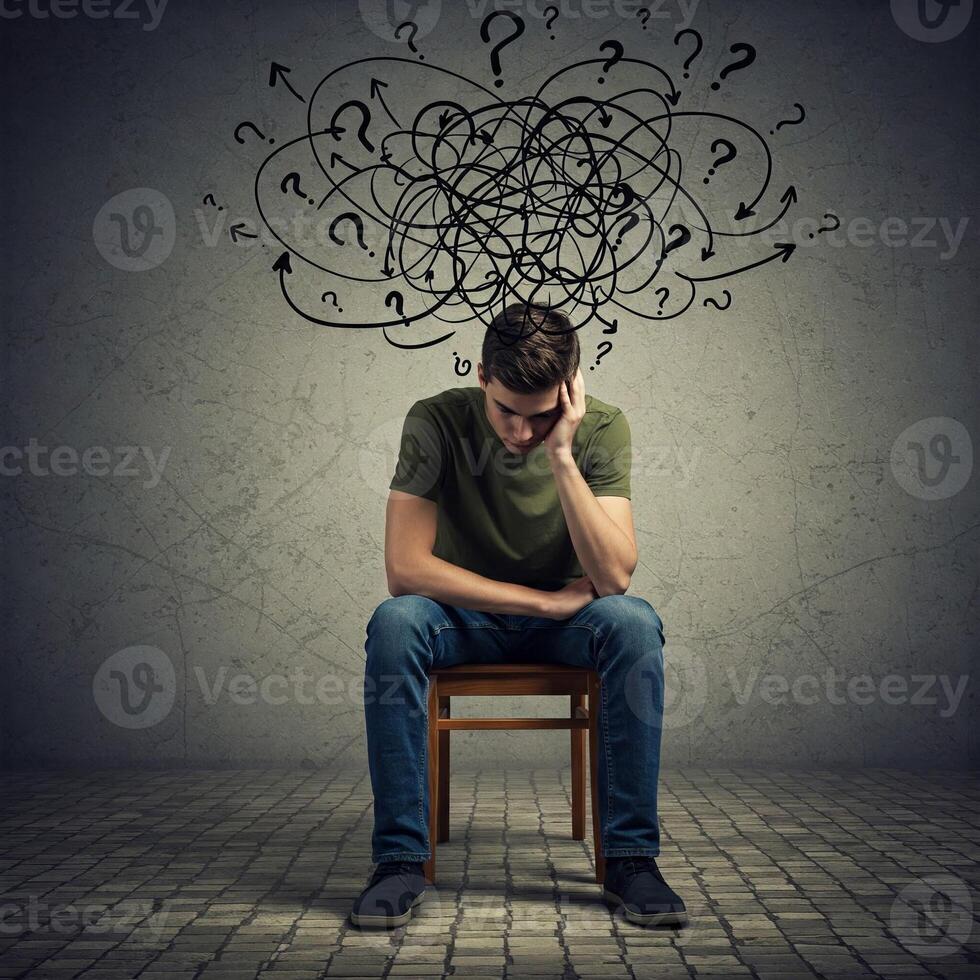 A man sitting on a chair with question marks above his head photo