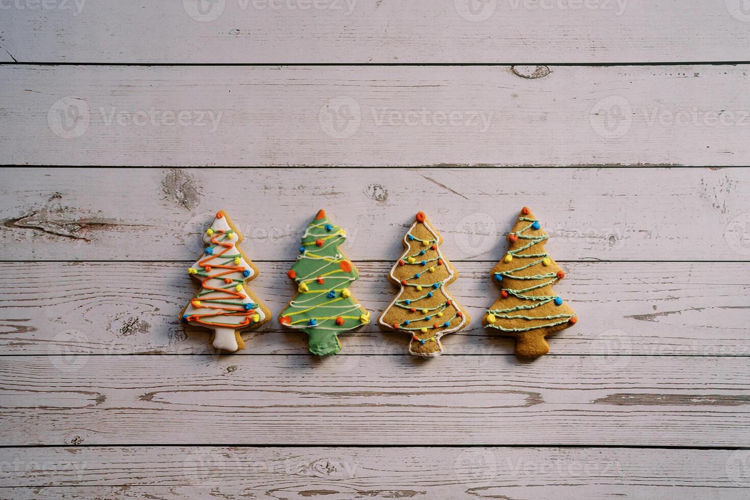 Christmas tree cookies with colorful icing lie on a light wooden table photo