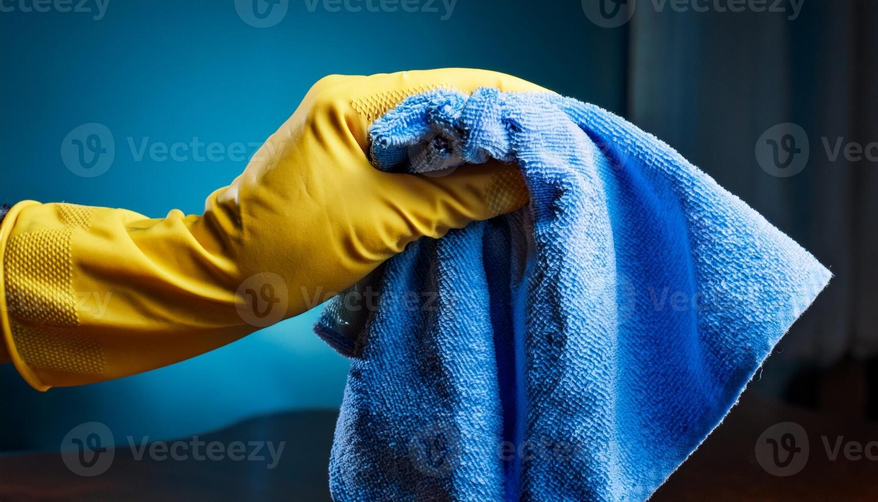 Cleaning Activity With a Yellow Gloved Hand Holding a Blue Cloth in a Well-Lit Indoor Space photo