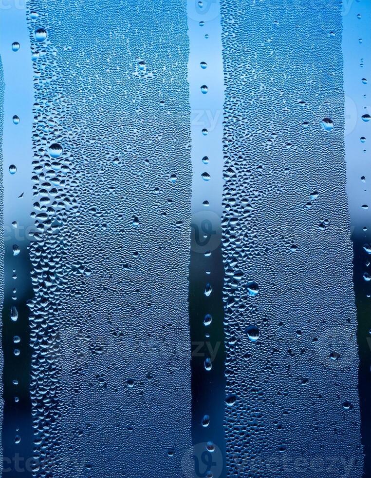 Morning Condensation Covers a Window Pane, Creating a Blurred View of the Outdoors in Soft Blue Tones photo