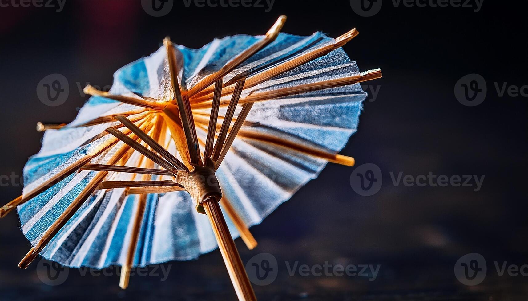 Miniature Cocktail Umbrella Resting on a Dark Surface With a Textured Background photo