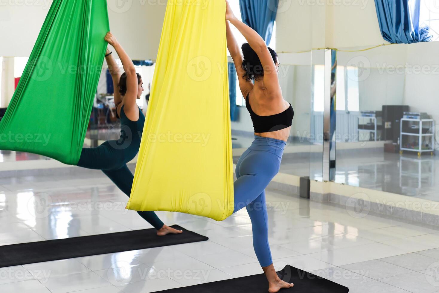 Young women making aerial or fly yoga pose indoors photo
