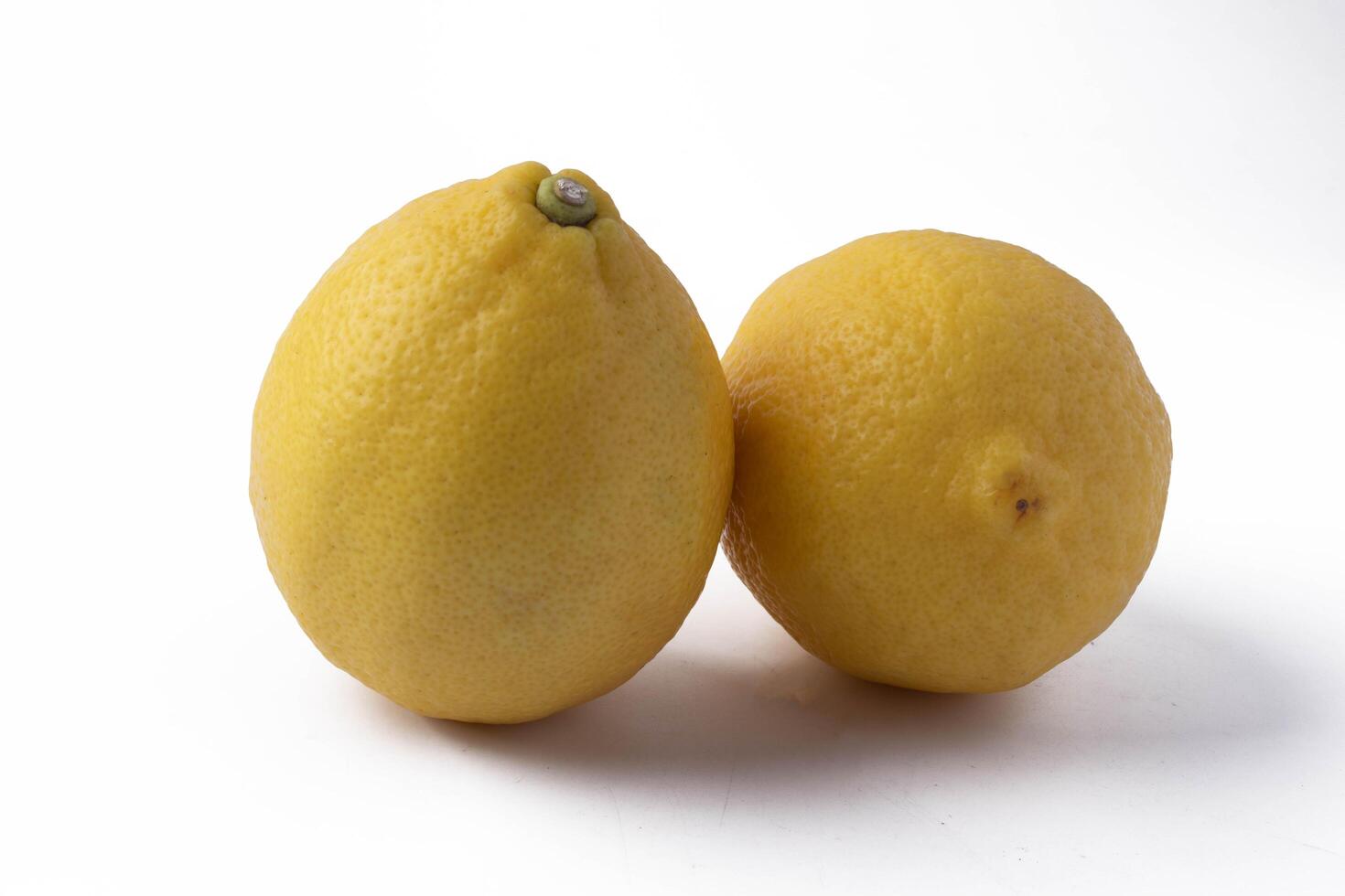 Two fresh lemons on white background, showcasing their vibrant yellow color and textured skin. lemons are positioned side by side, highlighting their natural shape and citrus appeal photo