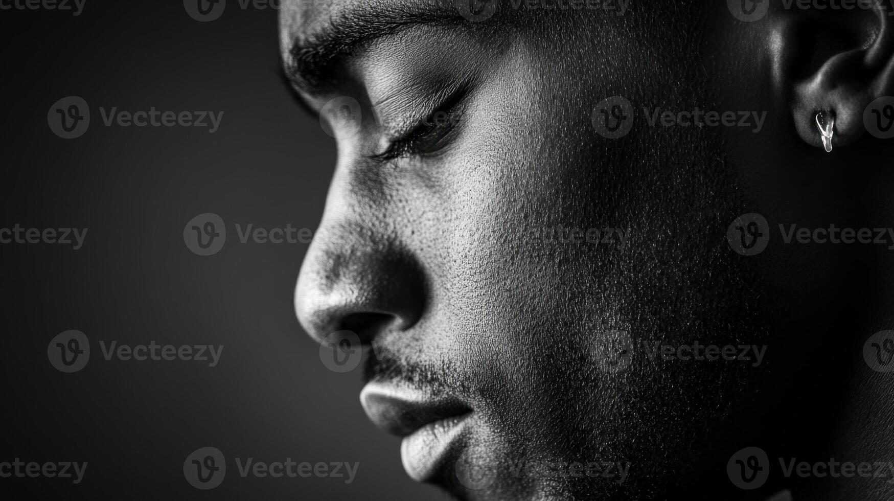 black and white portrait captures man in profile, highlighting his contemplative expression and textured skin. lighting emphasizes details of his face and earring photo