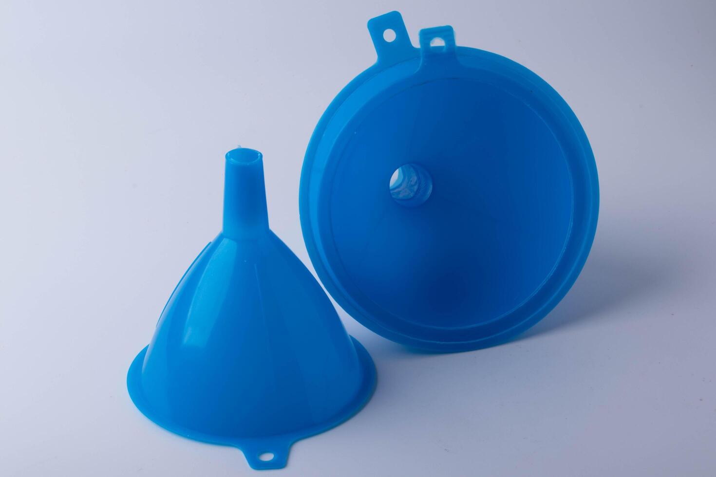 Two blue plastic funnels are displayed against plain background, one standing upright and other lying flat, showcasing their simple design and functionality photo