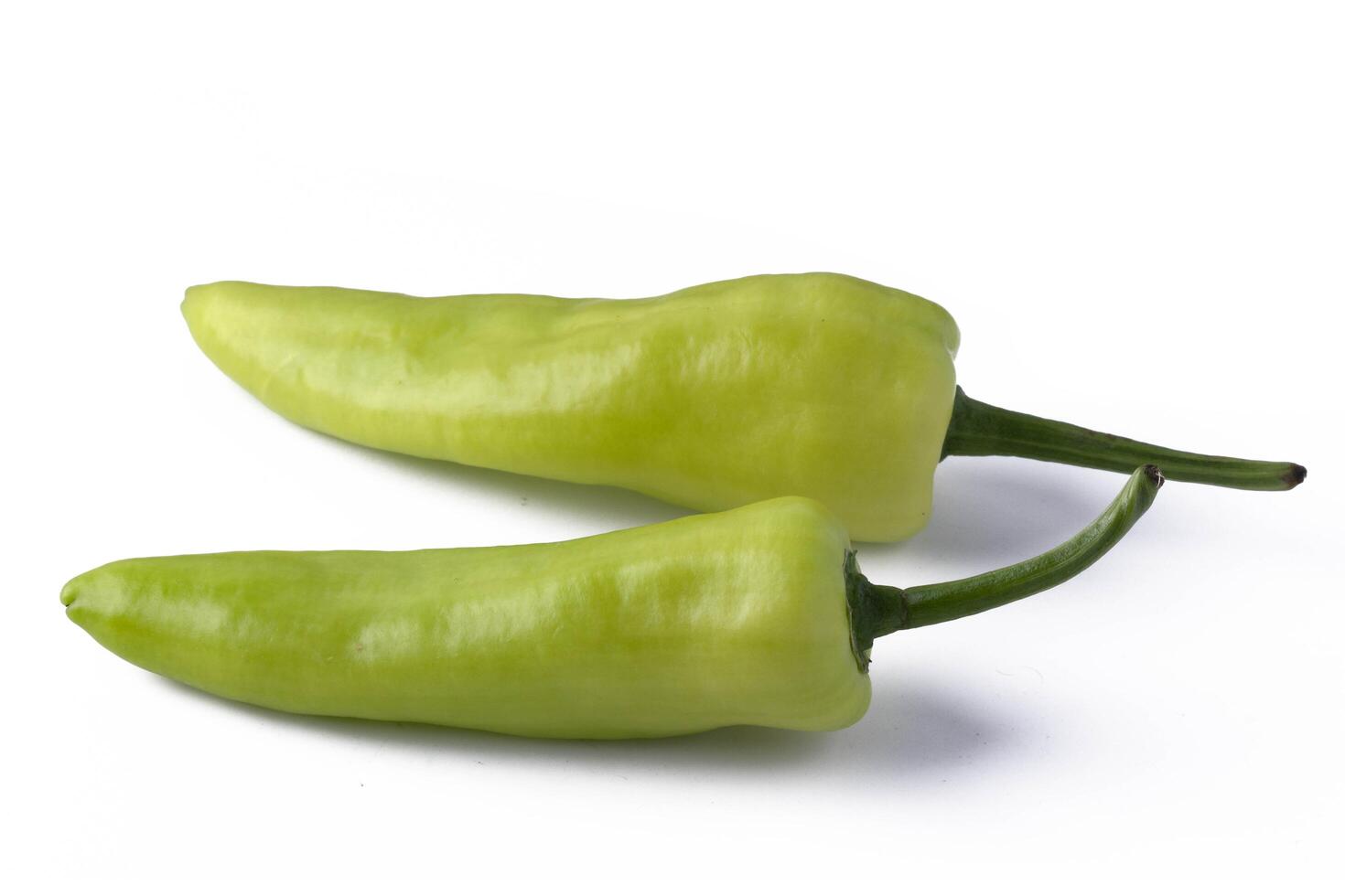 Two fresh green chili peppers with stems on white background, showcasing their vibrant color photo