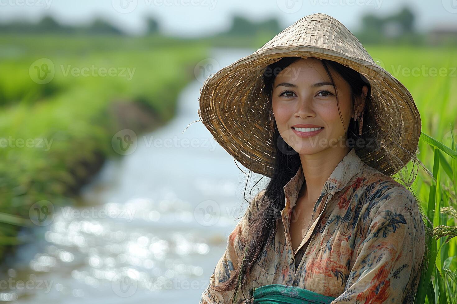 a woman managing an irrigation system in a rice field, standing on a levee with water flowing nearby, wearing traditional farming attire and smiling under bright sunlight photo