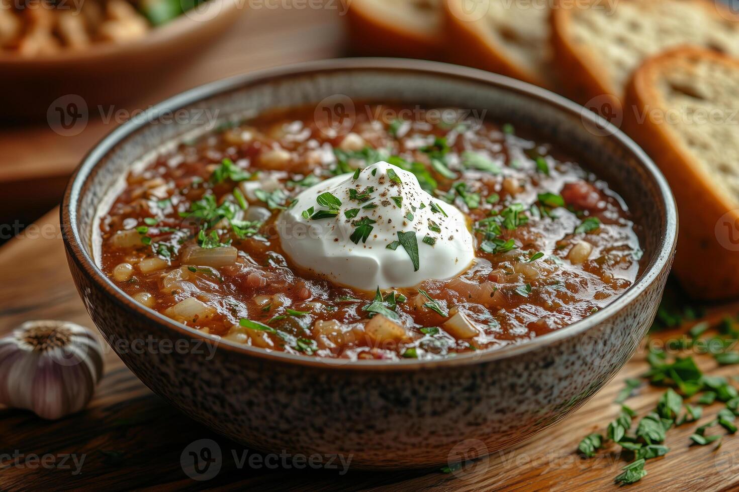 a steaming bowl of Ukrainian borscht, topped with a dollop of sour cream, served with rye bread and garlic photo