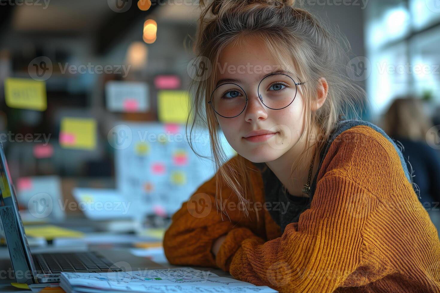 a teenage girl developing a mobile app, sitting at her desk with a laptop and sketches of app wireframes photo