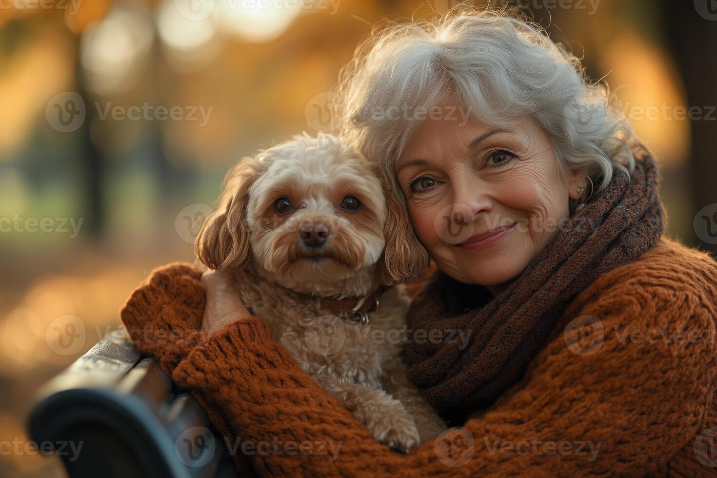 A senior woman and her dog share a joyful, intimate embrace in the autumn park photo
