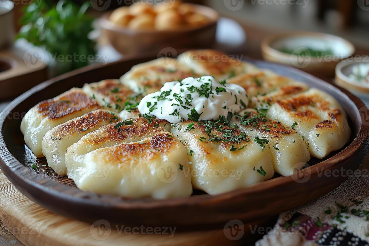 a traditional Eastern European table setting with freshly baked pierogi served on a rustic wooden plate, garnished with sour cream and herbs photo