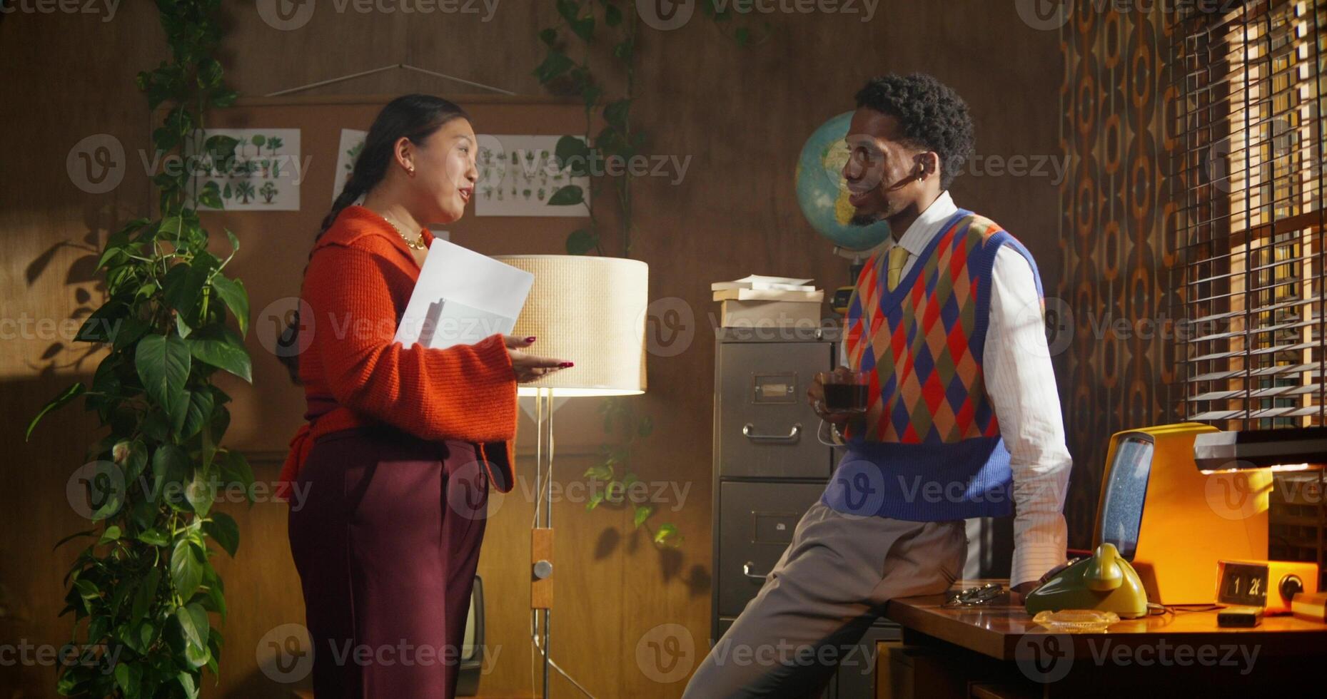 Two people standing in front of a desk talking photo
