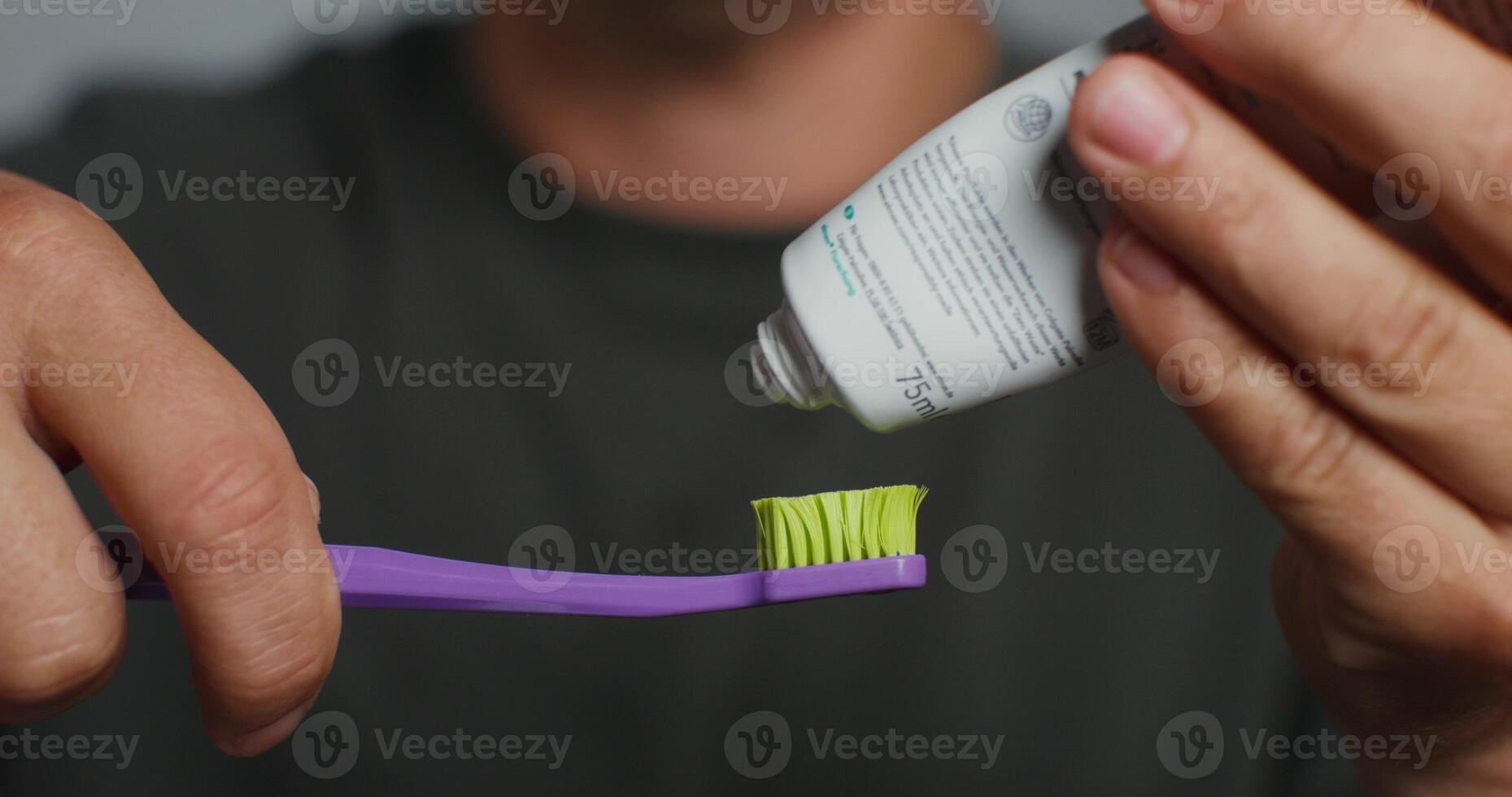 A man squeezes toothpaste onto a brush photo