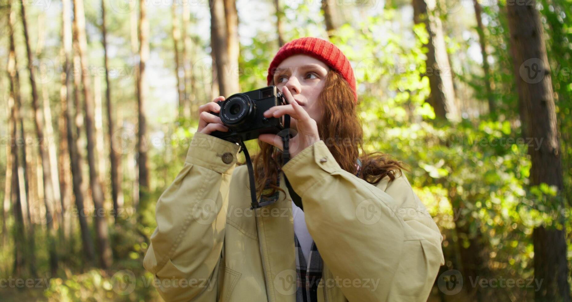 A woman in a red hat is taking a photo with a camera