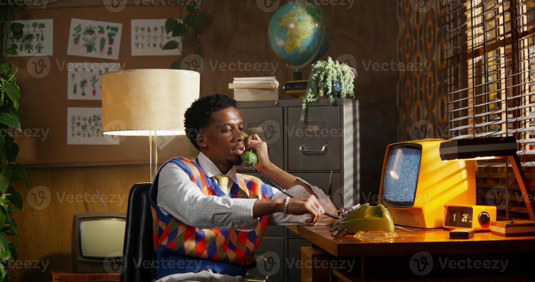 A man sitting at a desk talking on a phone photo