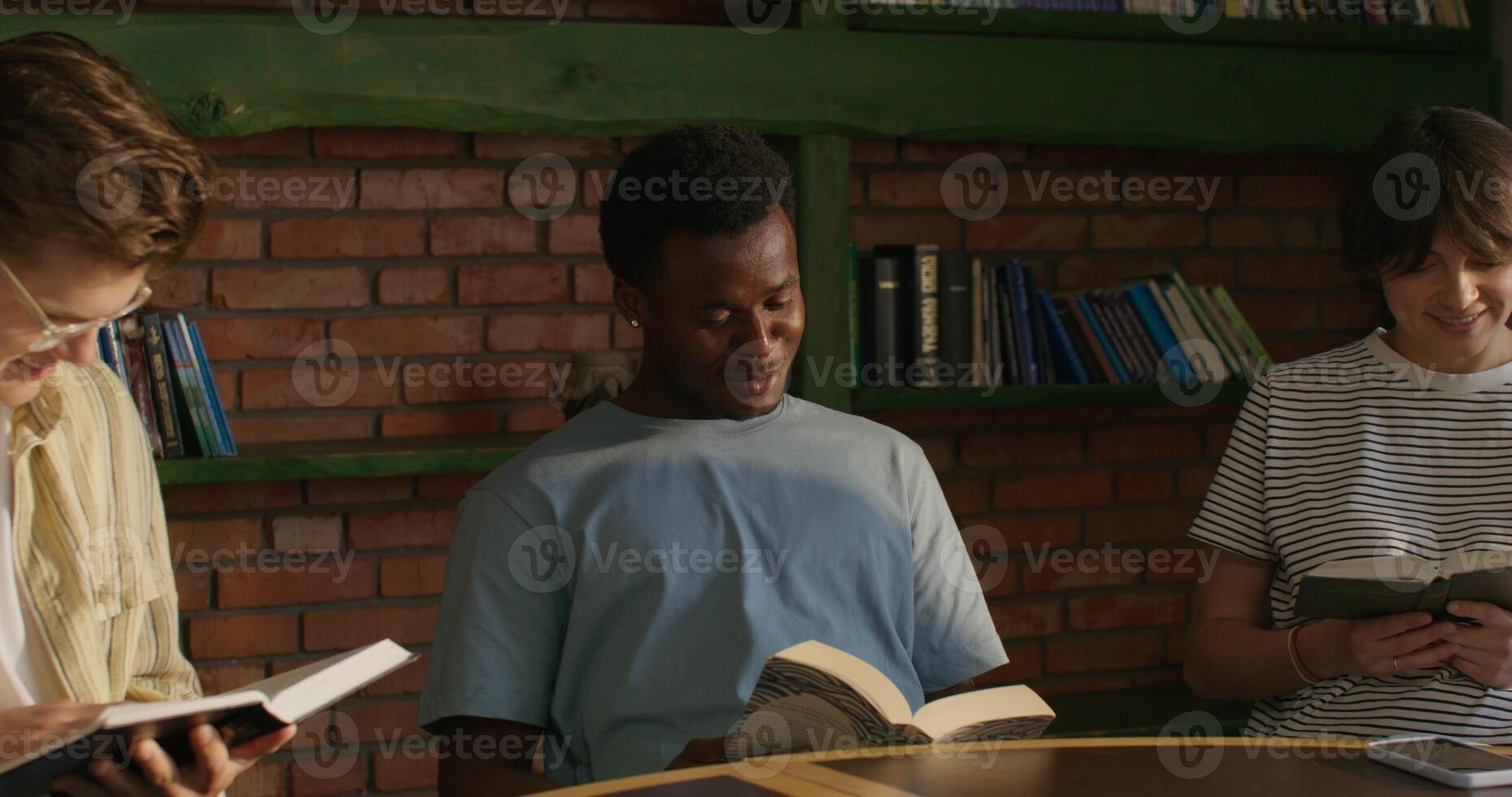Three young people sitting at a table reading books photo