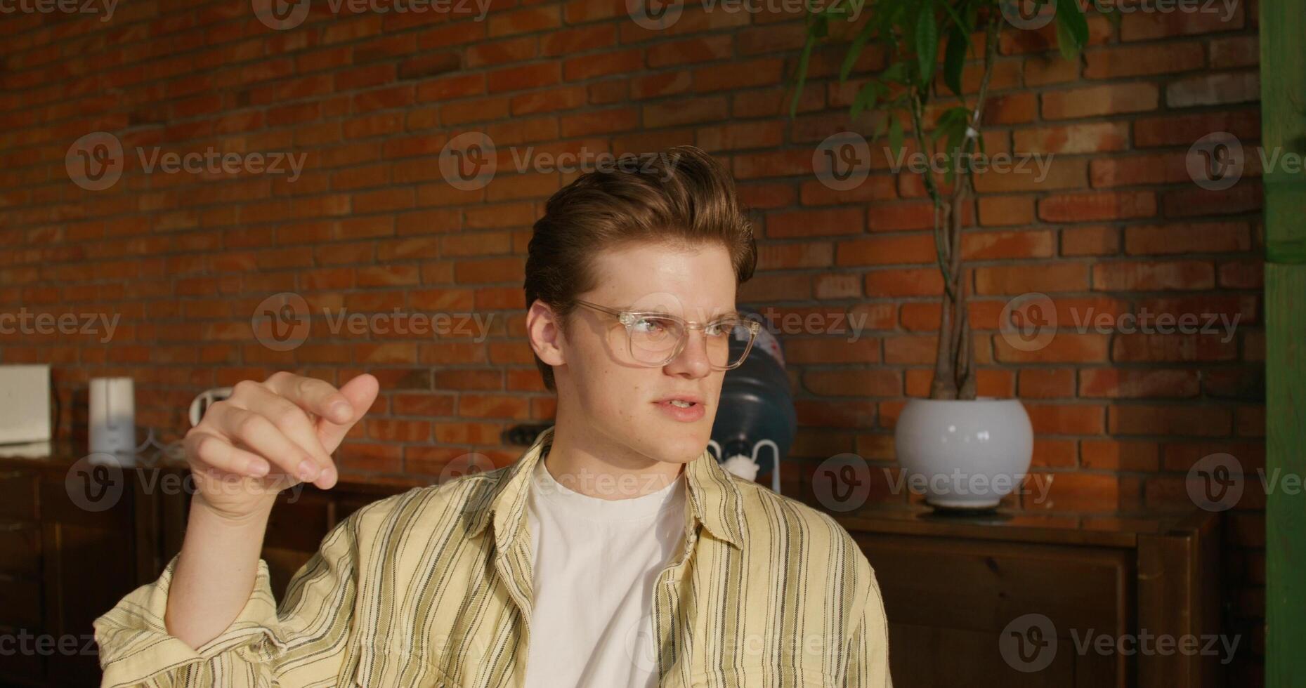 A young man wearing glasses pointing at something photo