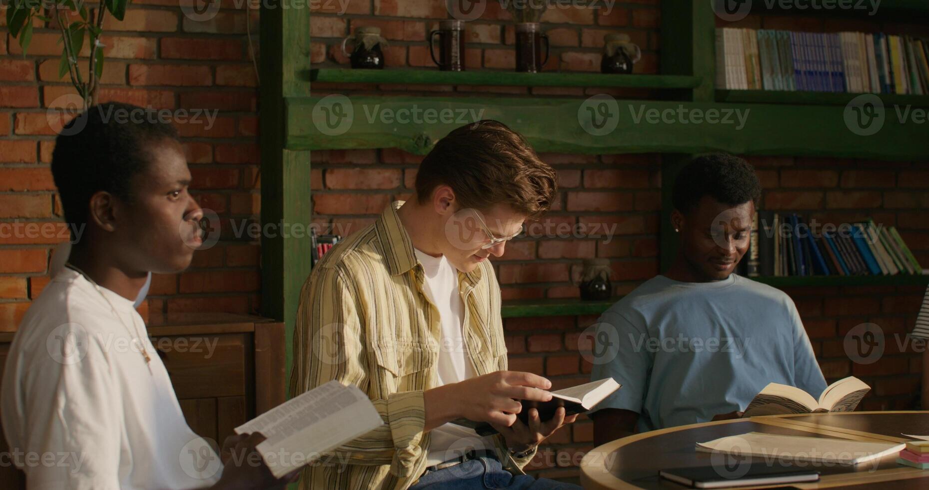 A group of young men sitting around a table reading books photo