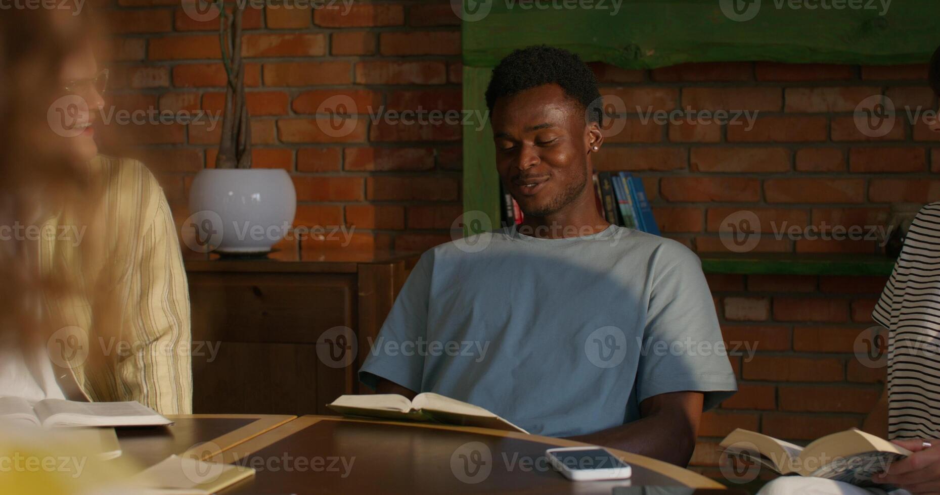 Three people sitting at a table with books photo