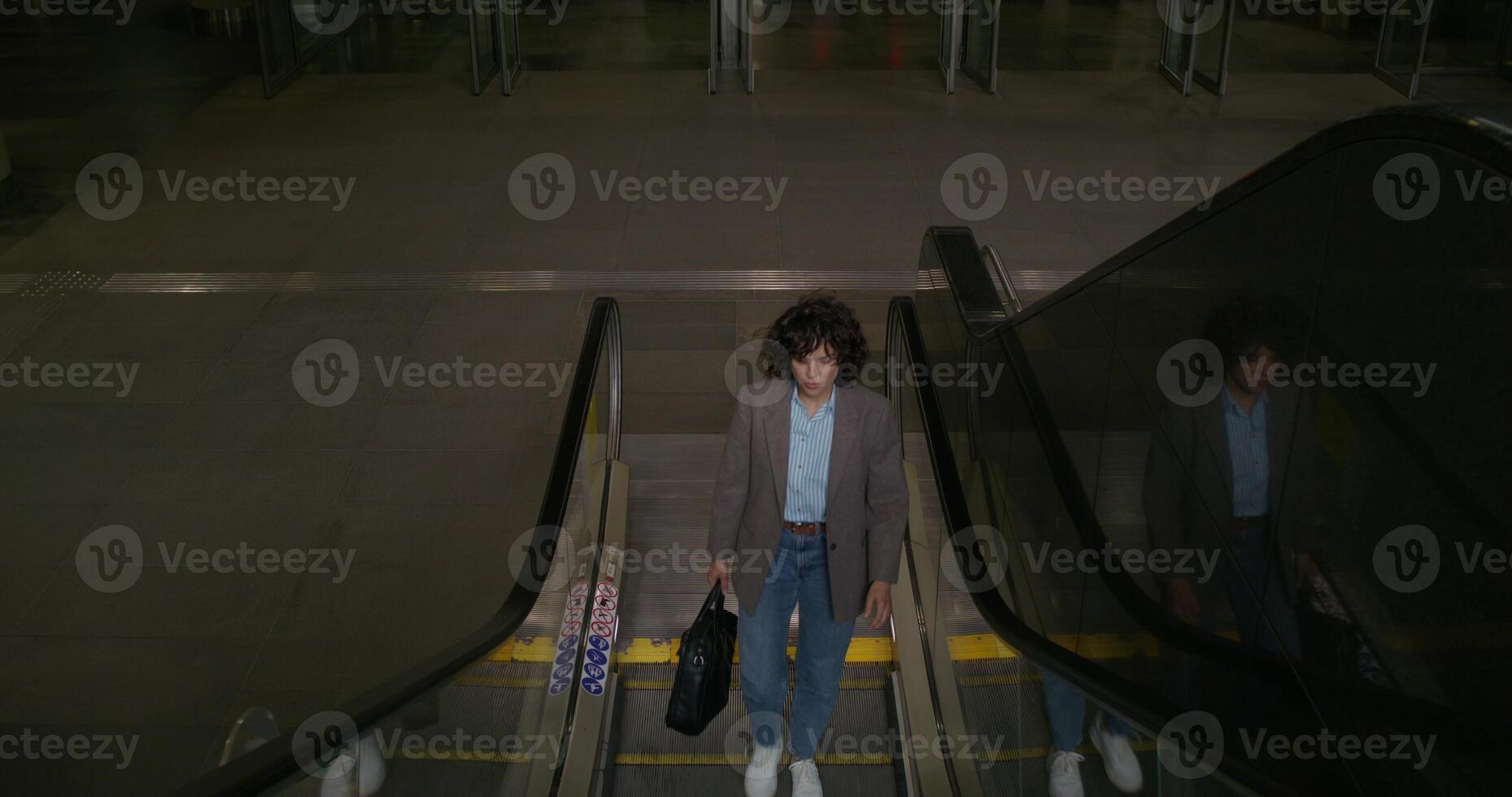 A woman is riding an escalator in an airport photo