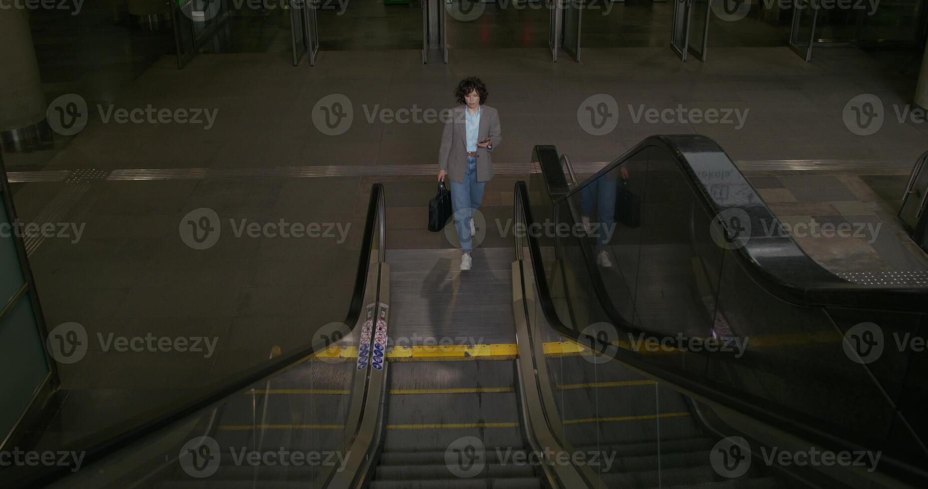 A woman walking up an escalator at an airport photo