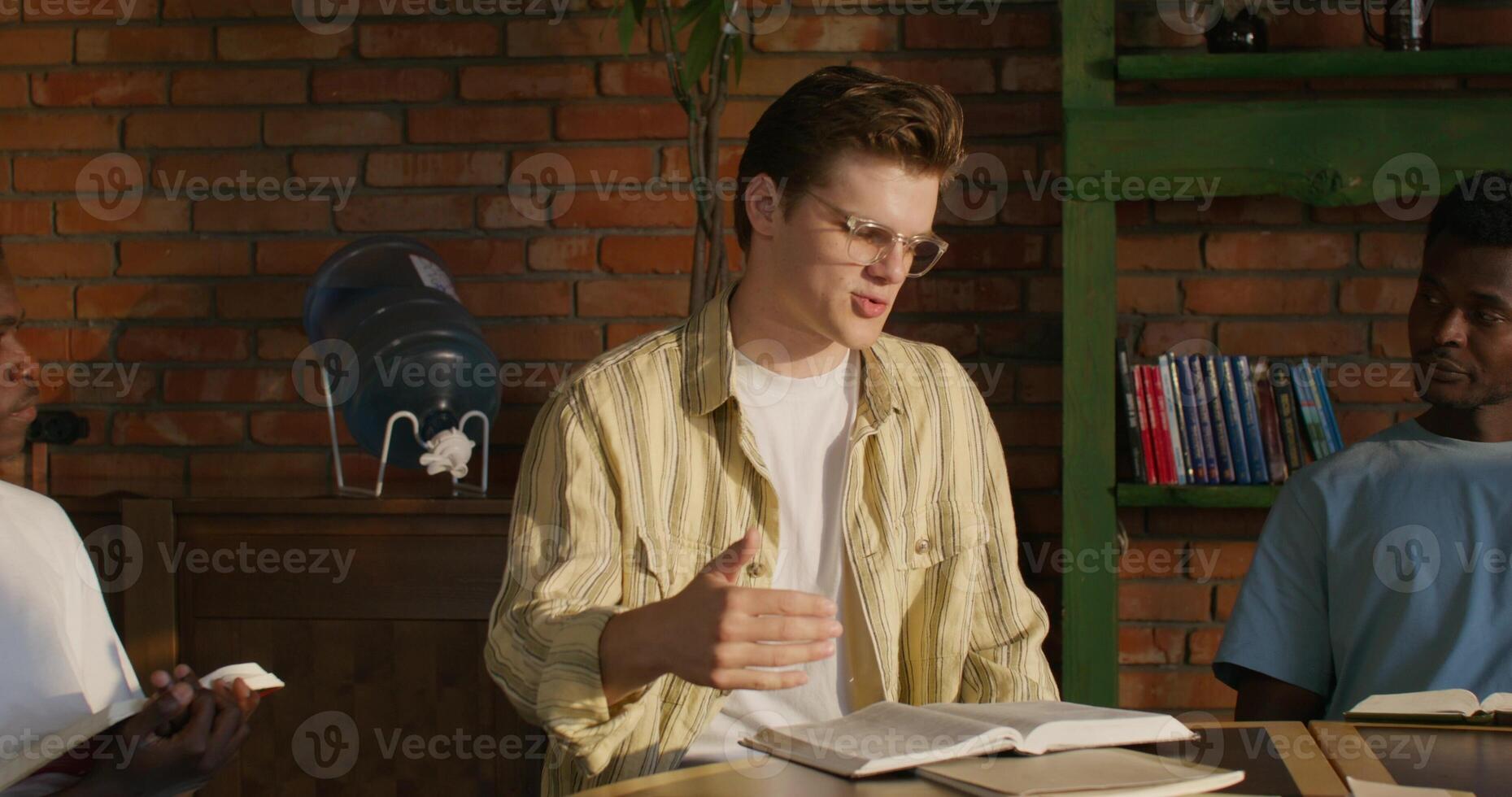 Three men sitting at a table with a book photo