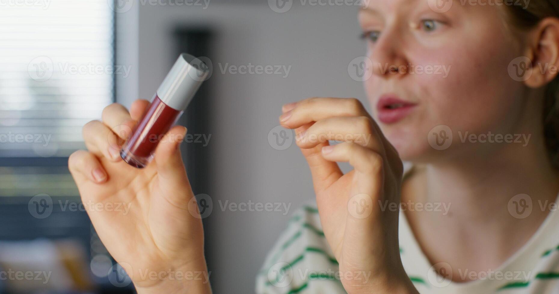 A woman holding a red lipstick in her hand photo
