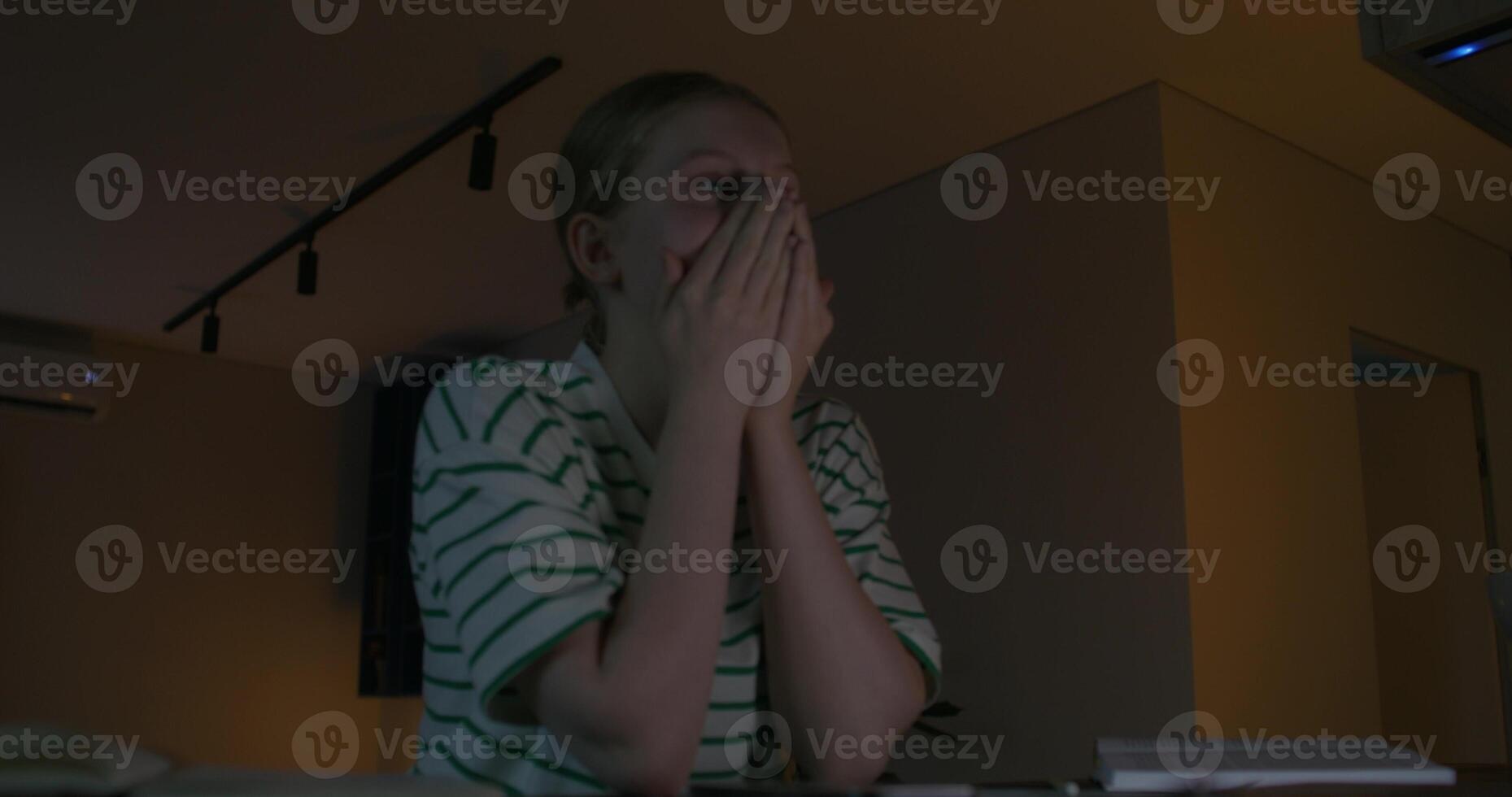 A woman sitting at a table with her hands on her face photo