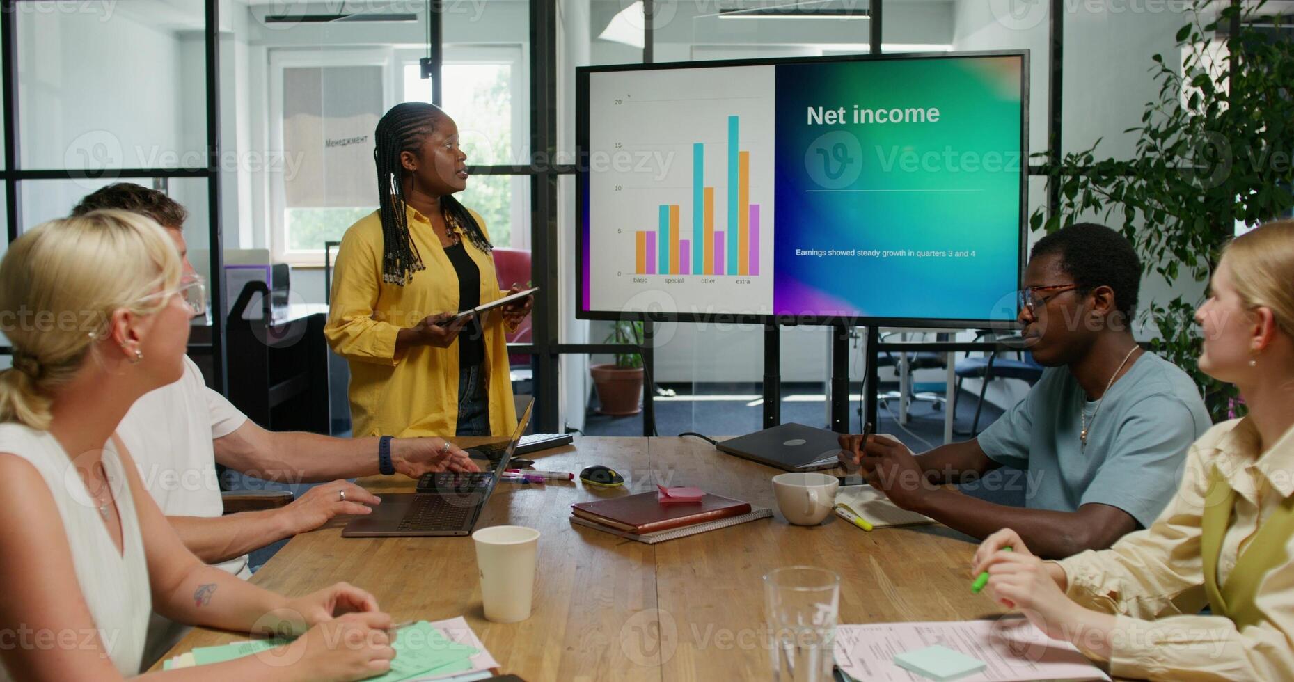 A group of people sitting around a table with a woman giving a presentation photo