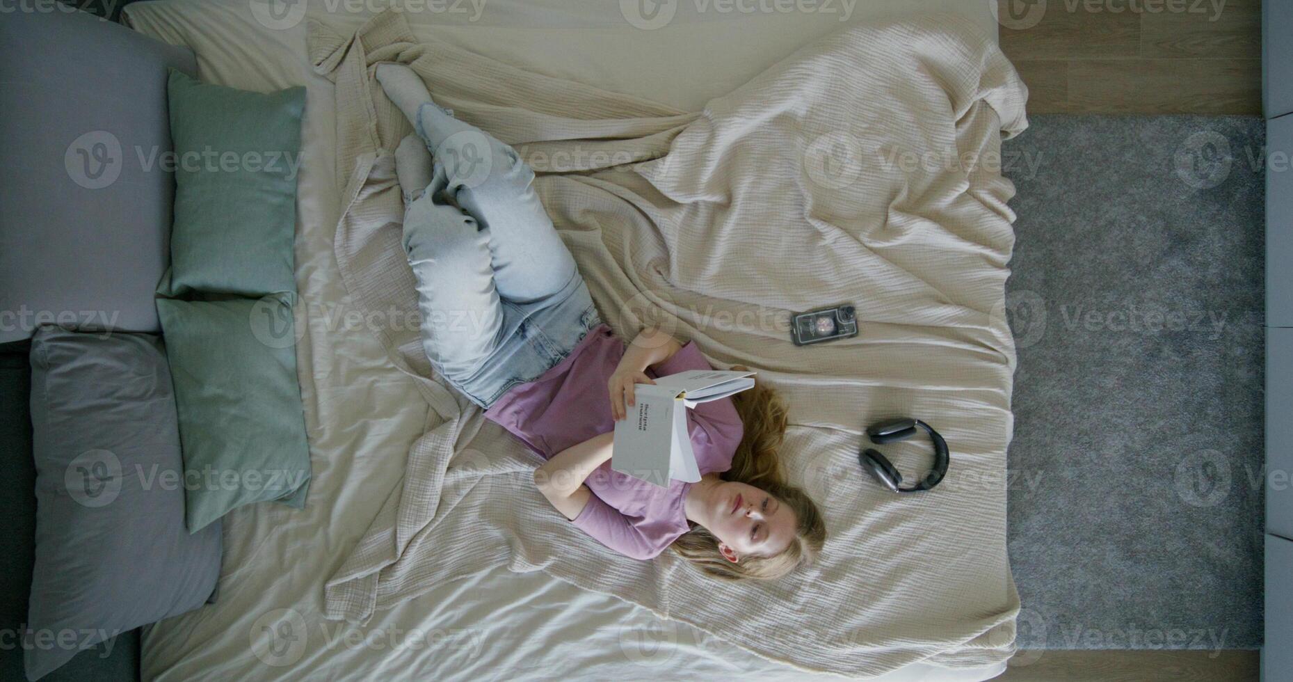 A woman laying on a bed with a book photo