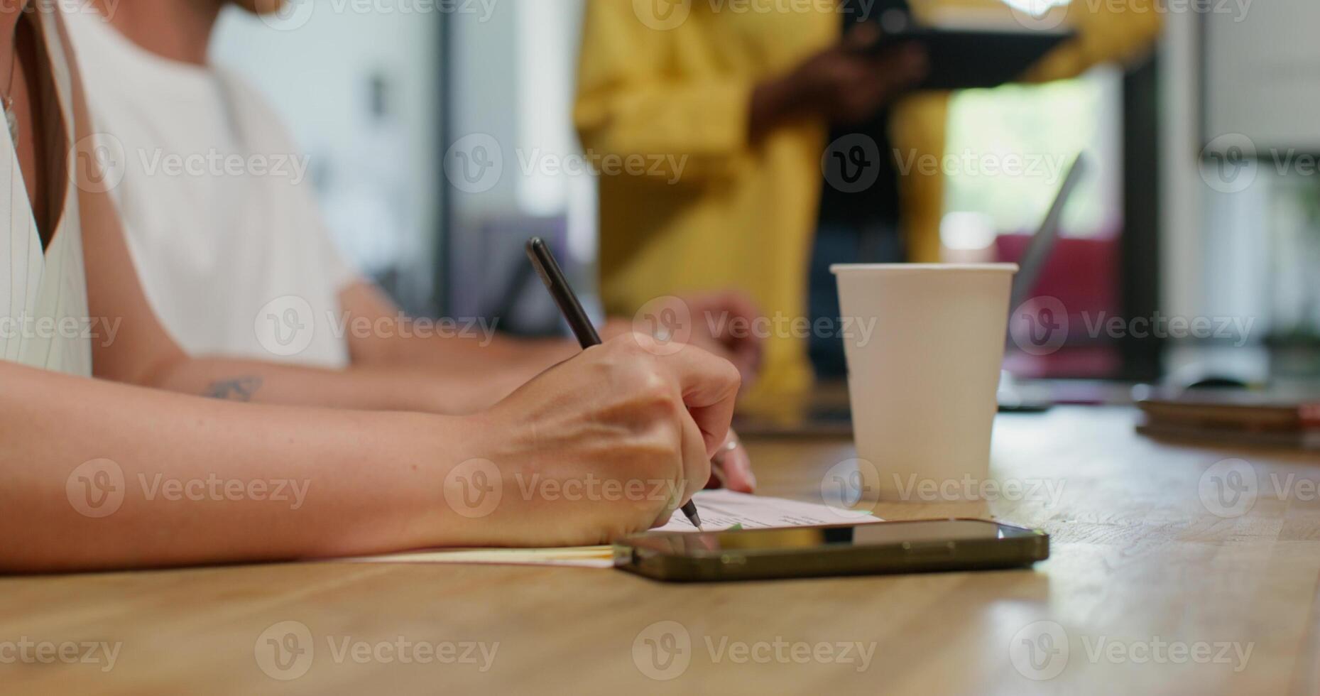 A woman writing on a piece of paper while sitting at a table photo