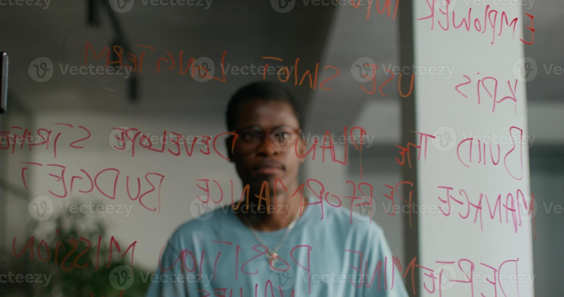 A man standing in front of a glass wall with writing on it photo