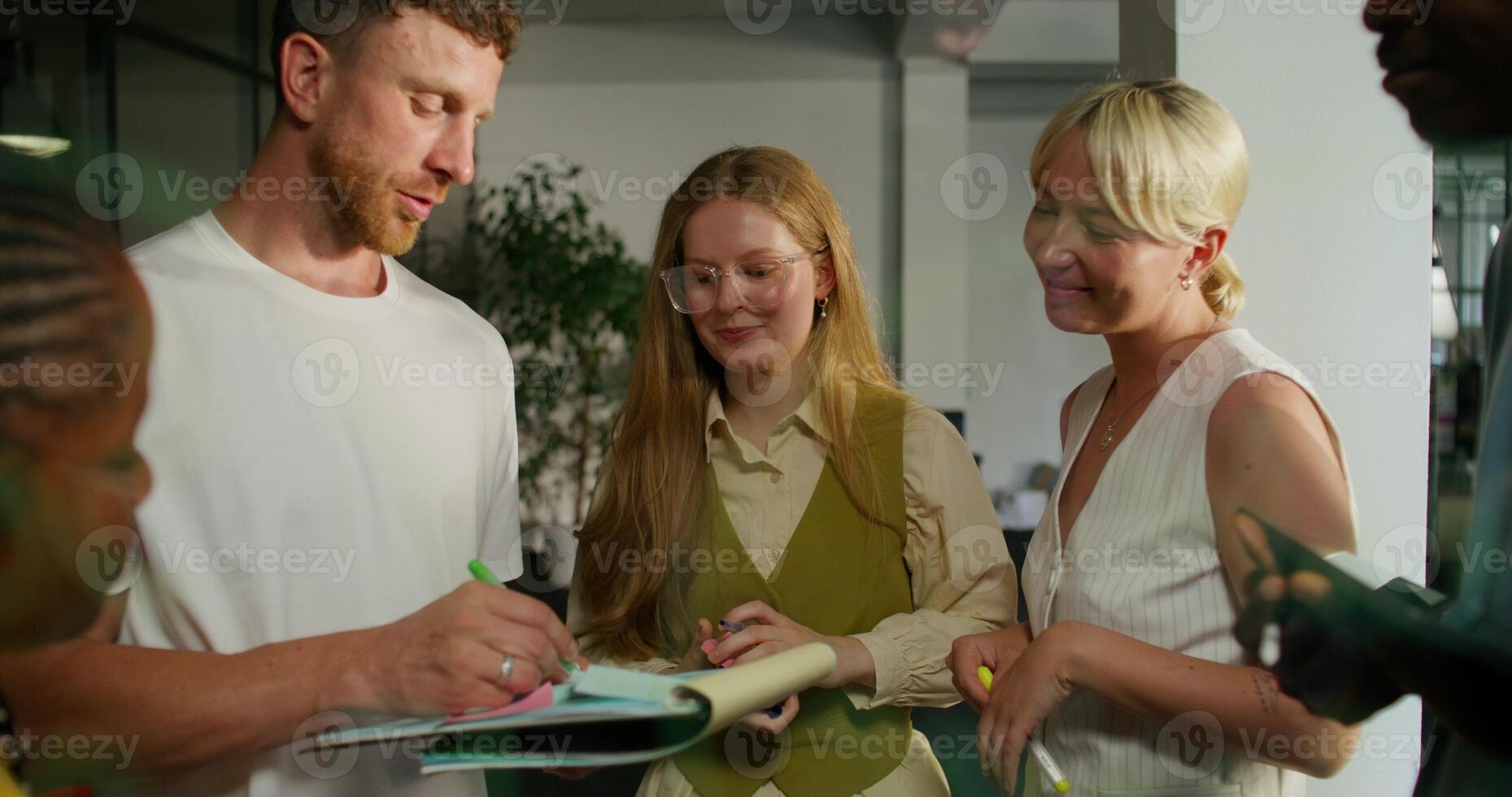 A group of people standing around a table with a notebook photo